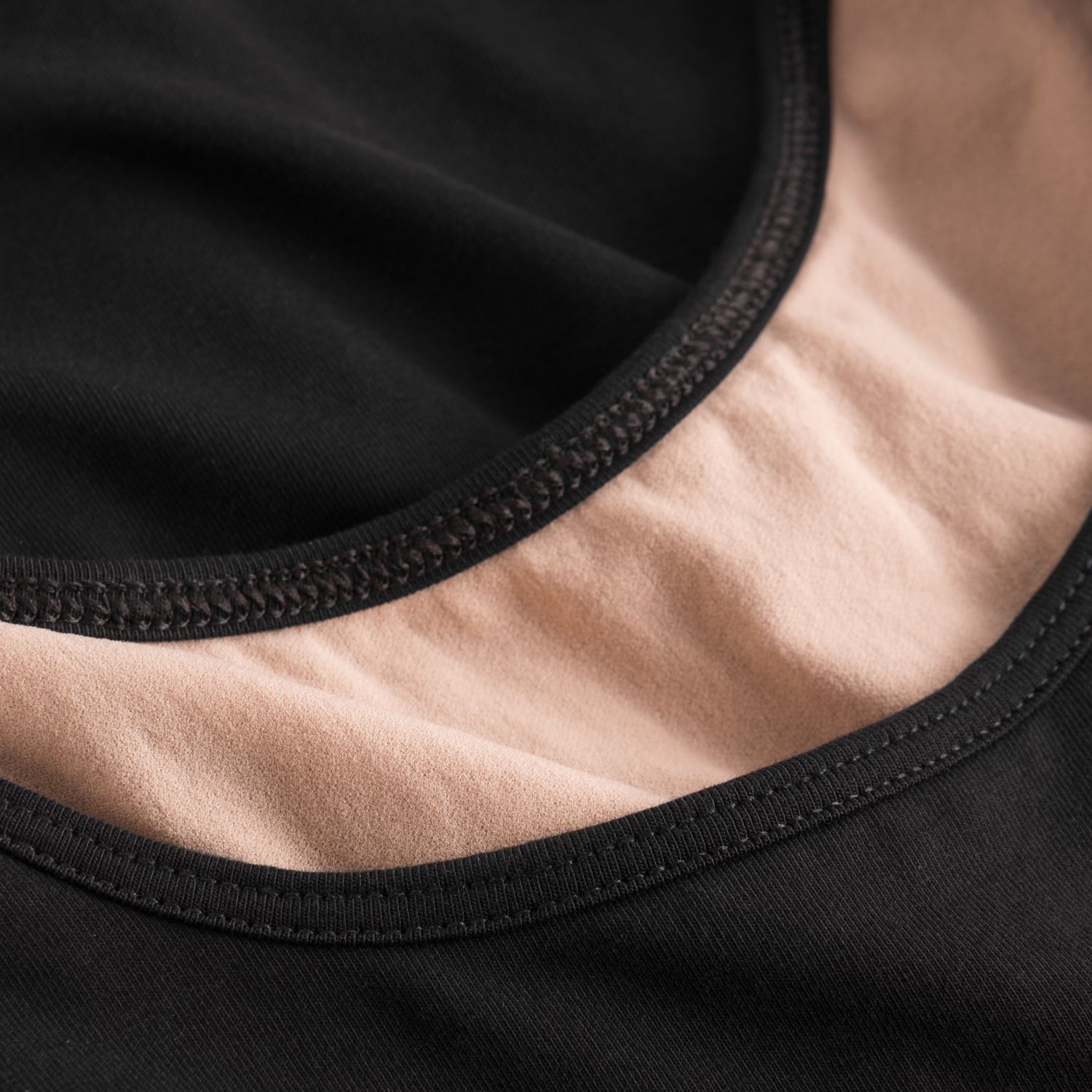 Nahaufnahme von Rumpfs R3110 Damen-Body in Schwarz mit pfirsichfarbenem Ausschnitt, sichtbaren Nähten und Spitzendetails.